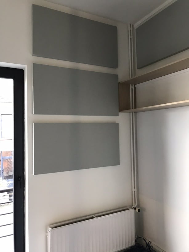 Panneaux muraux acoustiques gris en angle à côté d'une fenêtre