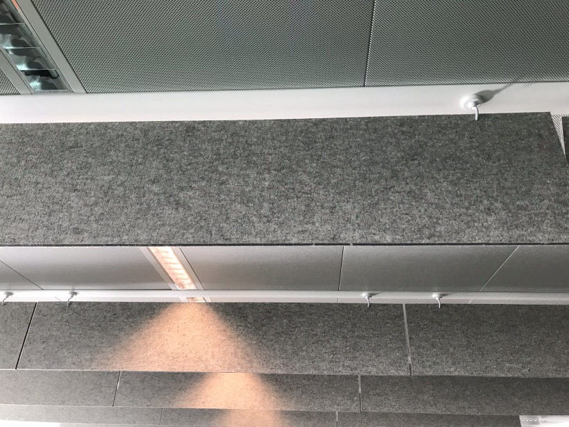 Baffle acoustique en feutre gris sous plafond métallique
