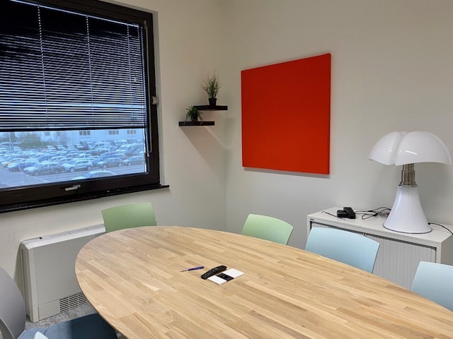 Panneau acoustique carré rouge en salle de réunion avec table ovale