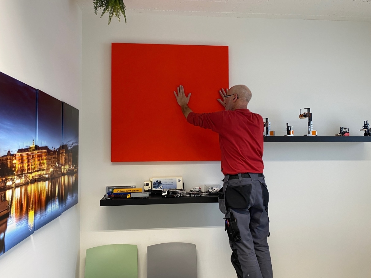 Pose d'un grand panneau mural acoustique rouge en showroom