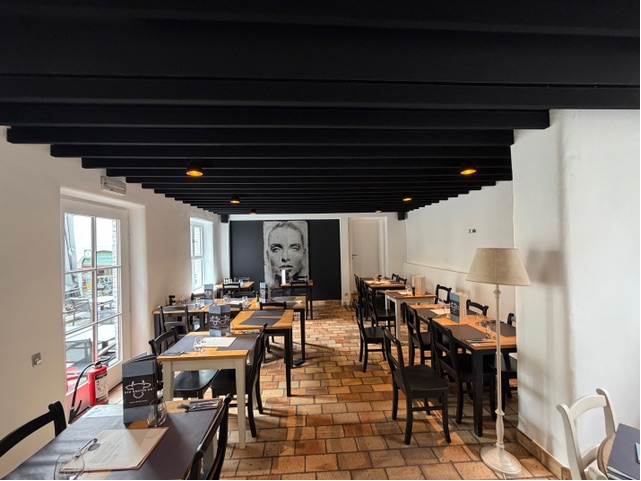 Baffles de plafond acoustiques noirs dans un bistrot avec œuvre d'art et tables en bois