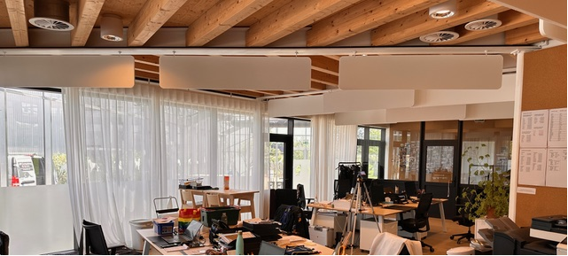 Baffles acoustiques blancs sous plafond à poutres bois dans un bureau open landscape