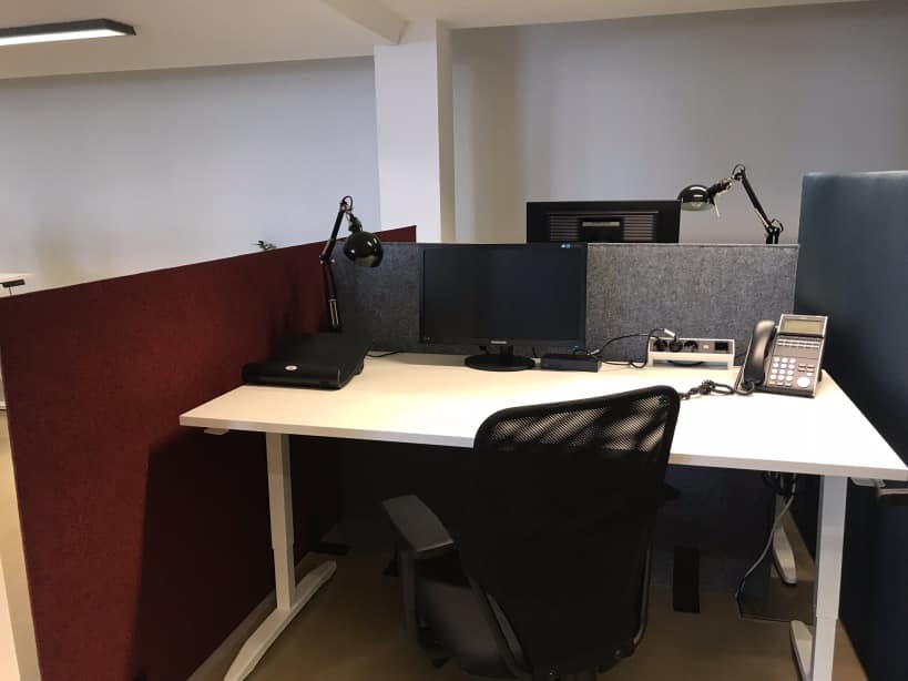 Cloisons acoustiques bordeaux et grises autour d'un poste avec téléphone