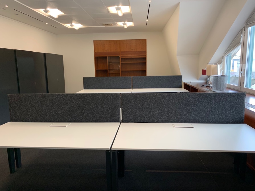 Desk-screens gris sur une rangée de bureaux dos-à-dos dans un bureau moderne