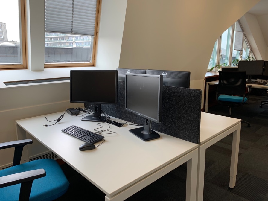 Écran de bureau acoustique gris entre doubles écrans dans un bureau lumineux