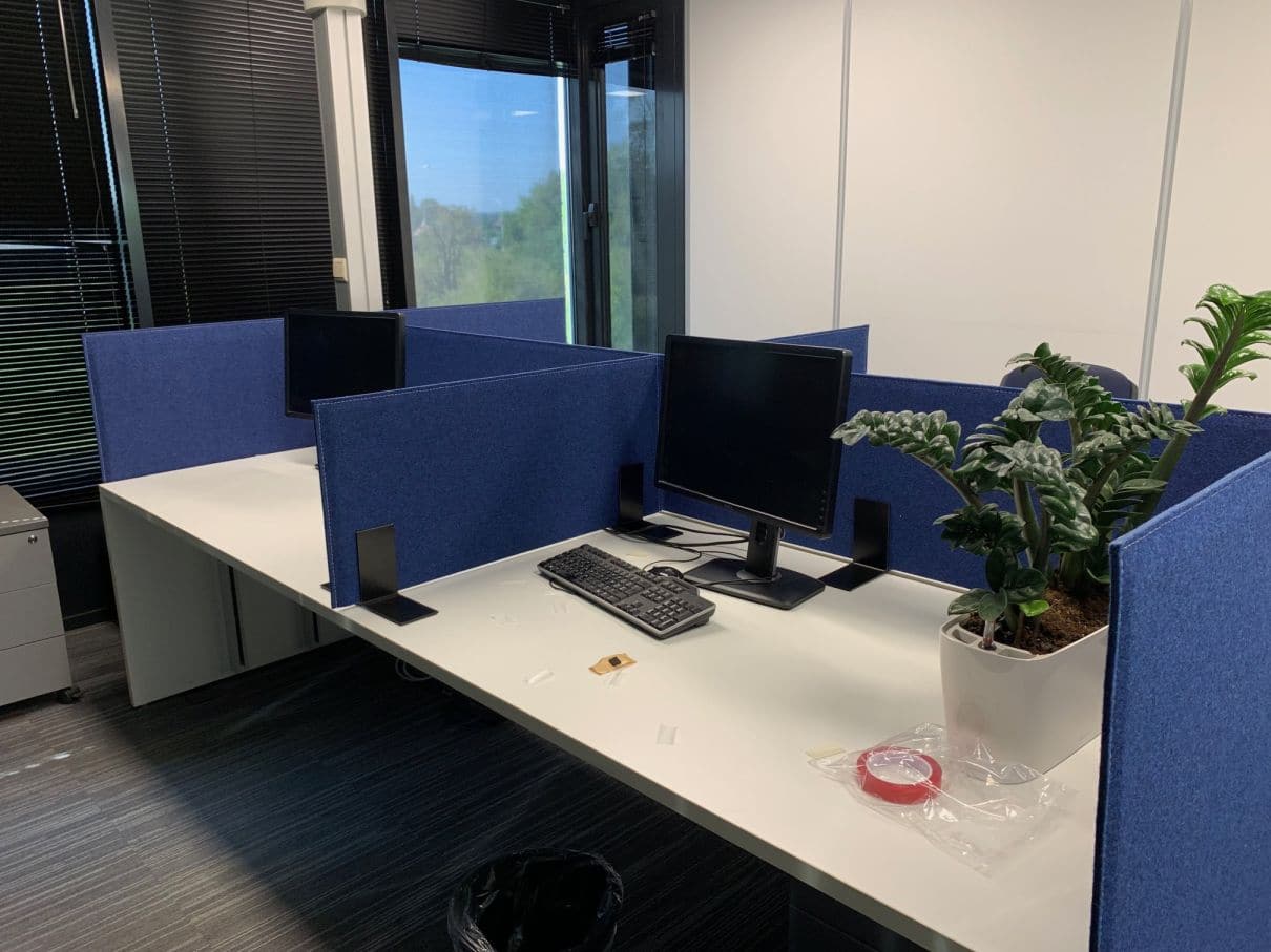 Cloisons acoustiques bleues entre bureaux dos-à-dos près de la fenêtre