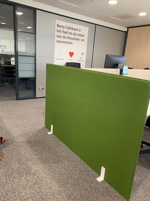 Cloison acoustique verte autoportante avec pieds en U dans un bureau