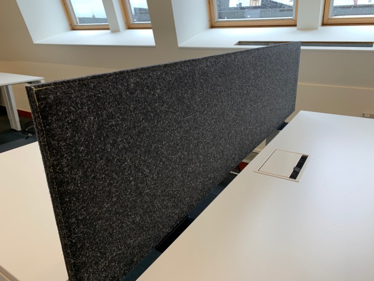 Écran de bureau acoustique anthracite entre bureaux dos-à-dos près de la fenêtre