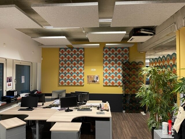 Îlots de plafond acoustiques au-dessus d'un poste de travail avec impression murale colorée