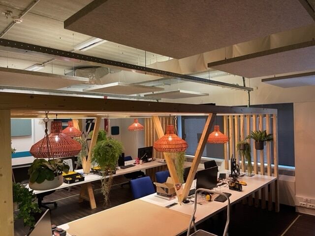 Îlots acoustiques beiges dans un espace de travail avec ossature bois et suspensions