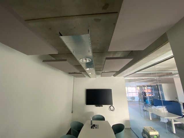 Îlots de plafond acoustiques gris dans une salle de réunion avec plafond béton