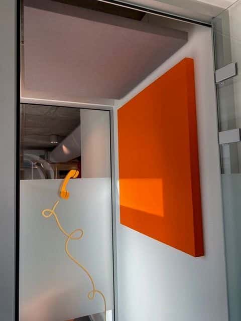Panneau mural acoustique orange dans une cabine téléphonique vitrée