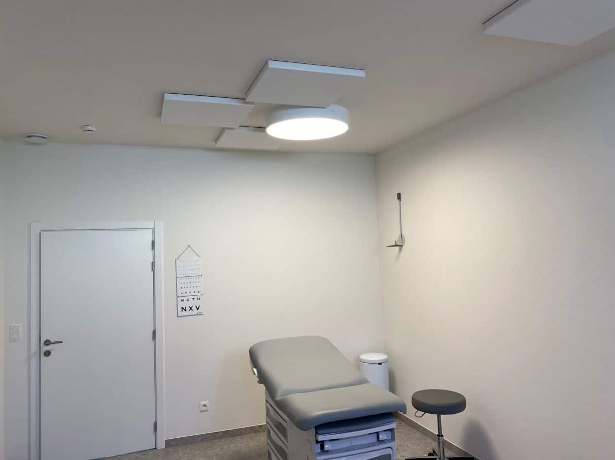 Panneaux de plafond acoustiques blancs dans une salle de consultation avec table d'examen