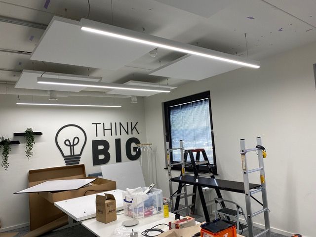 Îlots acoustiques blancs dans un bureau créatif avec mur « Think Big »