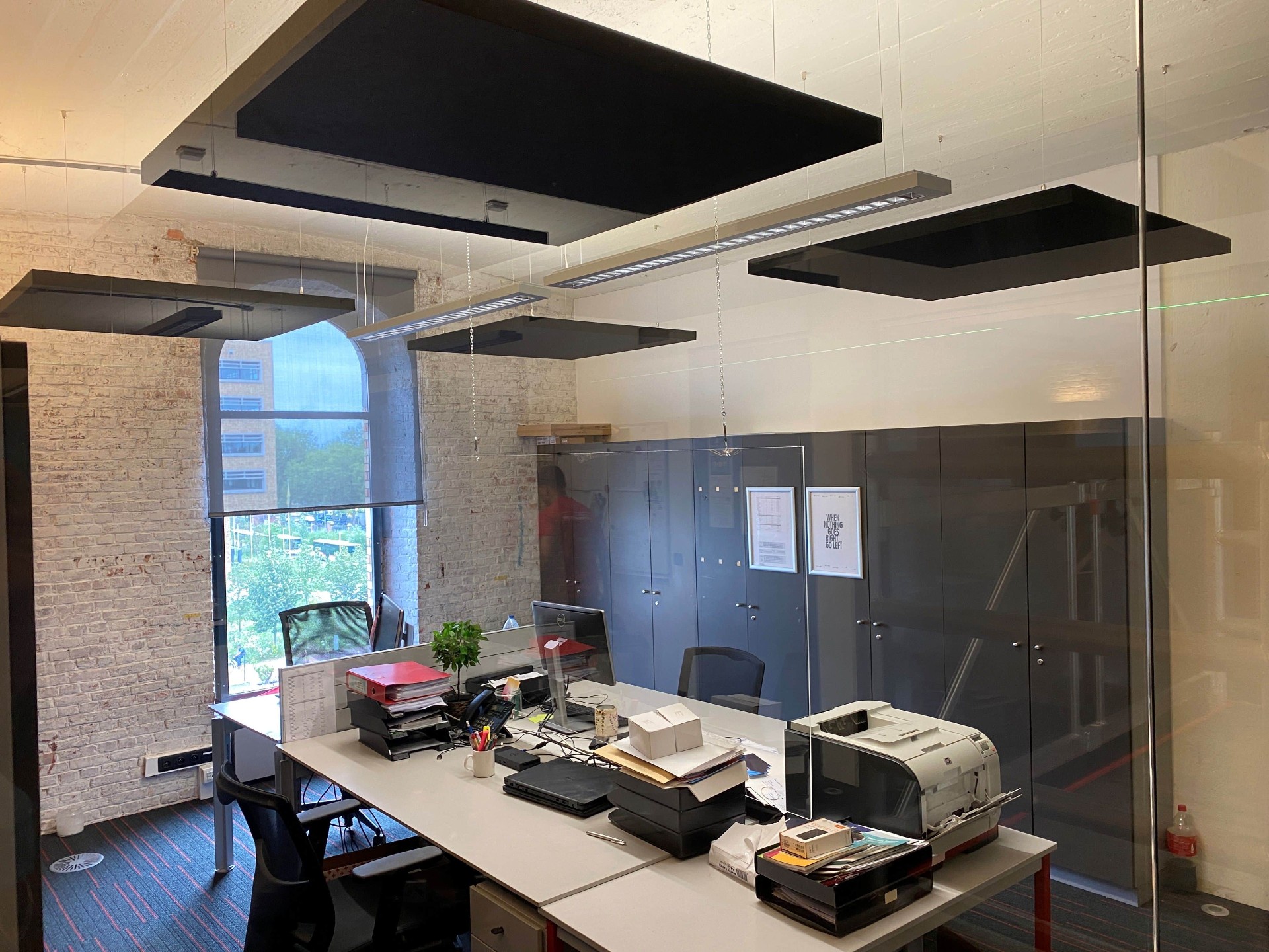 Îlots de plafond acoustiques noirs dans un bureau industriel avec mur en briques