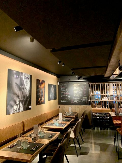 Îlot de plafond acoustique noir dans un établissement horeca avec éclairage d'ambiance