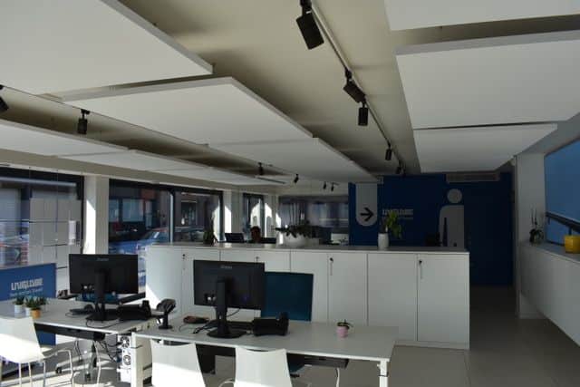 Îlots acoustiques blancs dans un bureau ouvert avec mur d'accent bleu