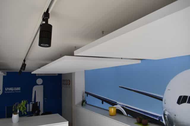 Îlots de plafond acoustiques blancs au-dessus du poste de travail d'une agence de voyage