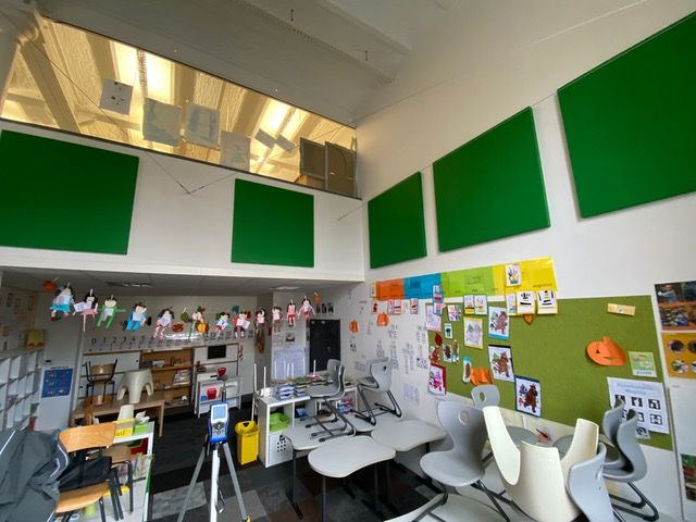 Panneaux muraux acoustiques verts en salle de classe avec haut plafond