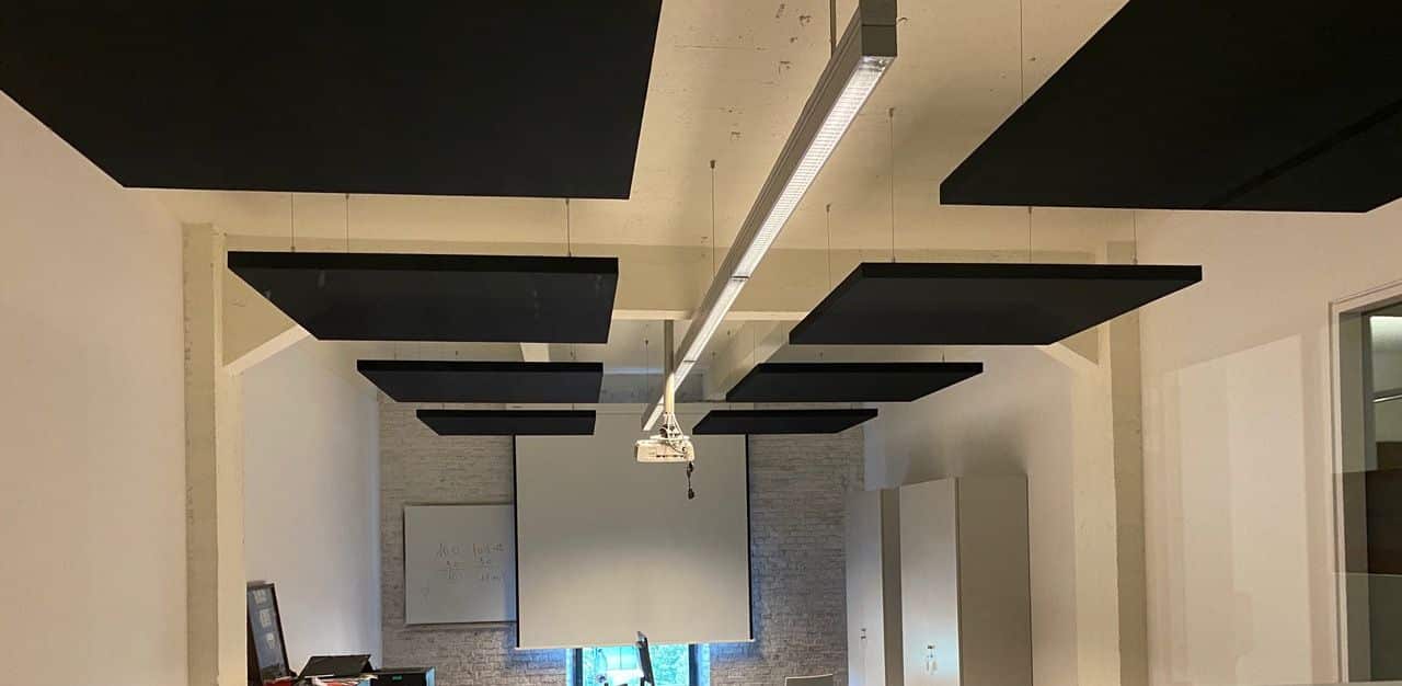 Îlots acoustiques noirs suspendus sous un haut plafond à poutres