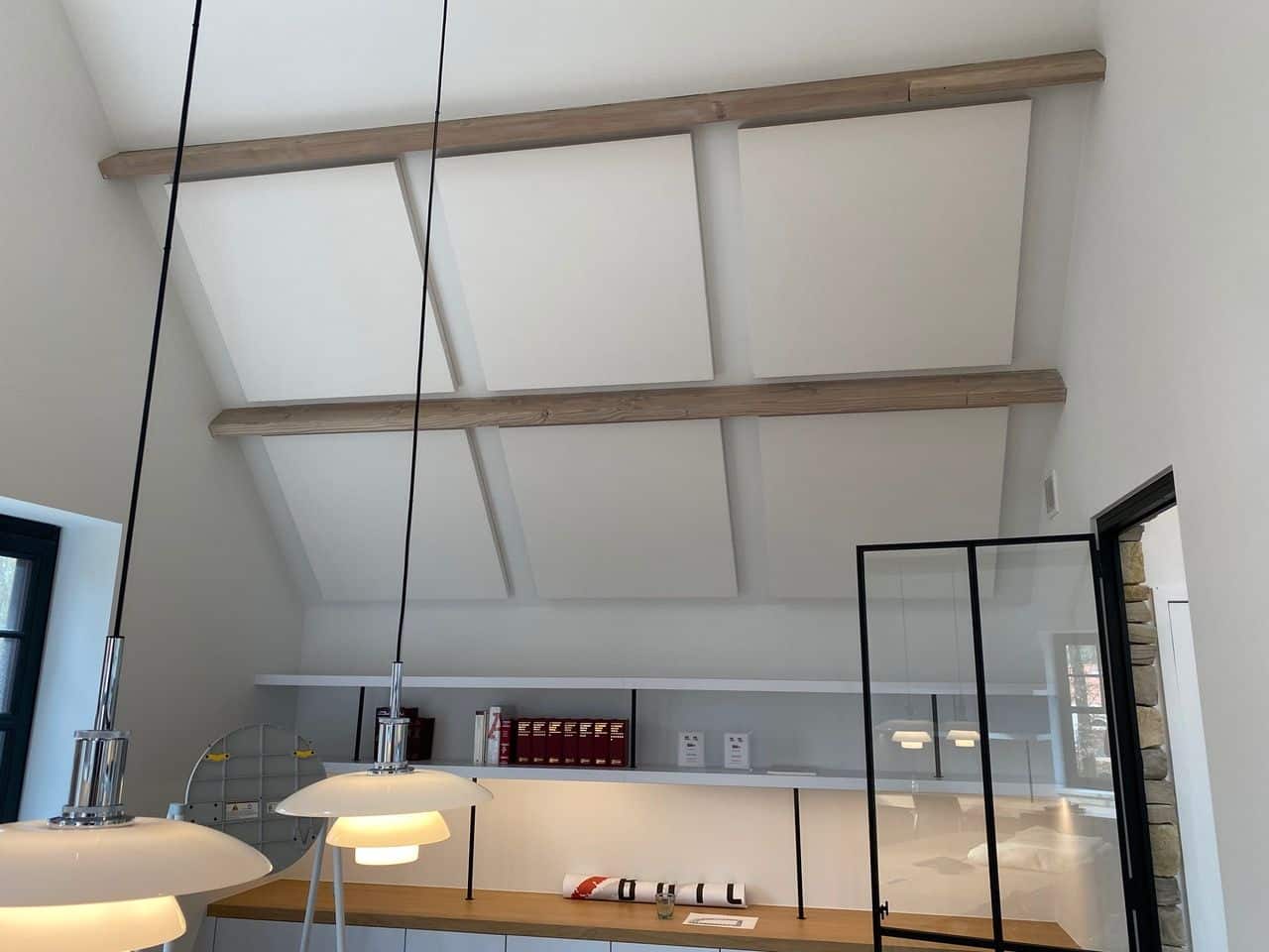 Panneaux acoustiques blancs contre plafond incliné à poutres en bois