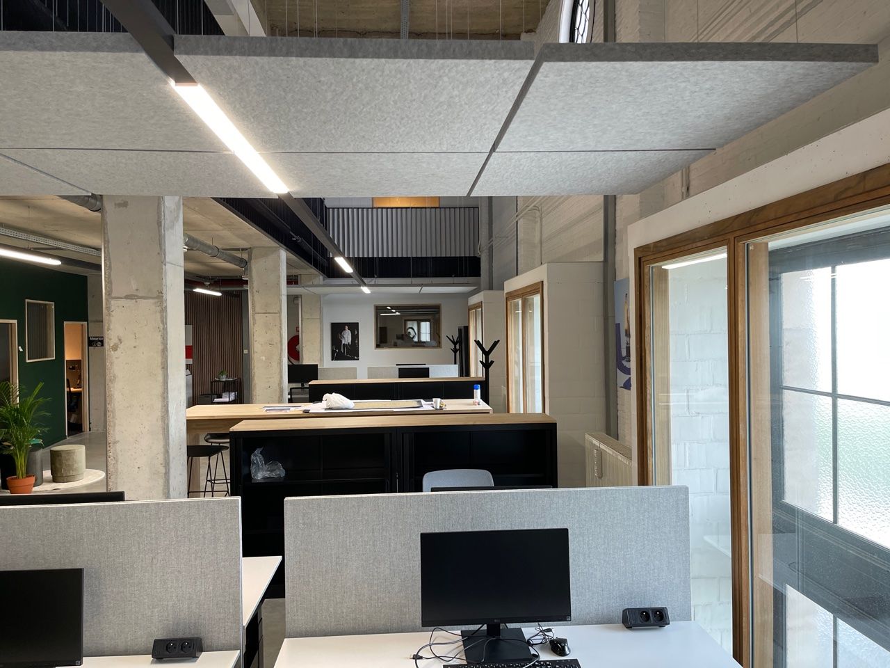 Îlot acoustique gris au-dessus de bureaux dans un loft de bureau