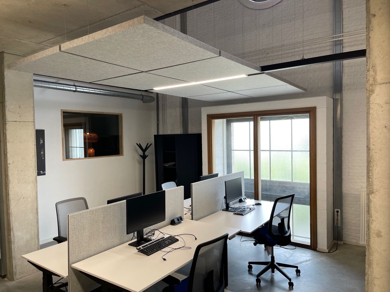 Îlots acoustiques gris sous plafond béton dans un espace de travail industriel
