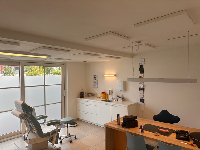 Îlots de plafond acoustiques blancs dans un cabinet de kinésithérapie avec table de soins