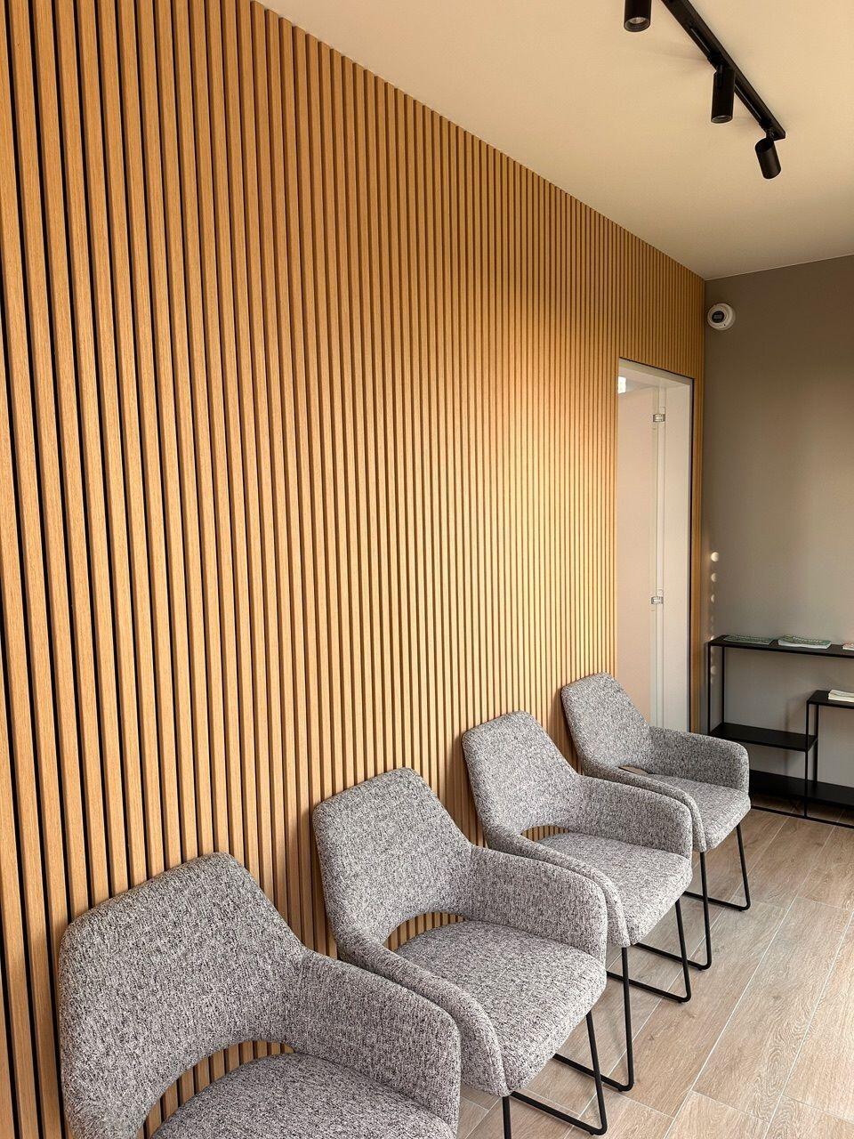 Mur en lattes de bois dans une salle d'attente de cabinet médical avec chaises grises