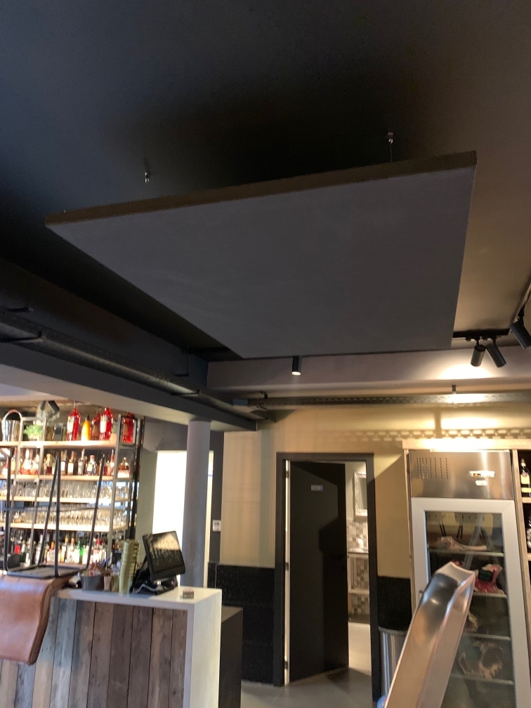 Îlot de plafond acoustique blanc au-dessus du bar dans un établissement horeca