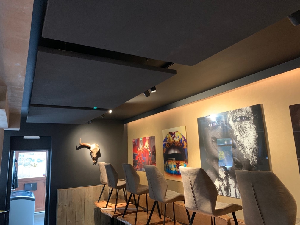 Îlots de plafond acoustiques foncés au-dessus d'un mur d'art en salle à manger