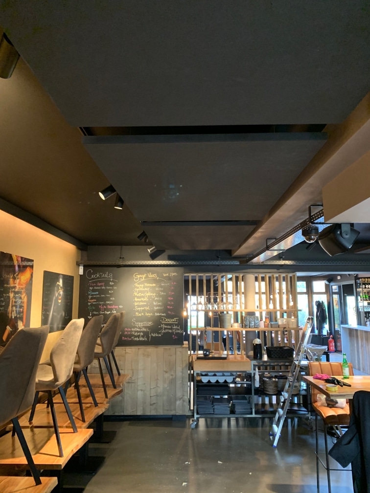 Îlots de plafond acoustiques au-dessus d'un bar à cocktails avec ardoise