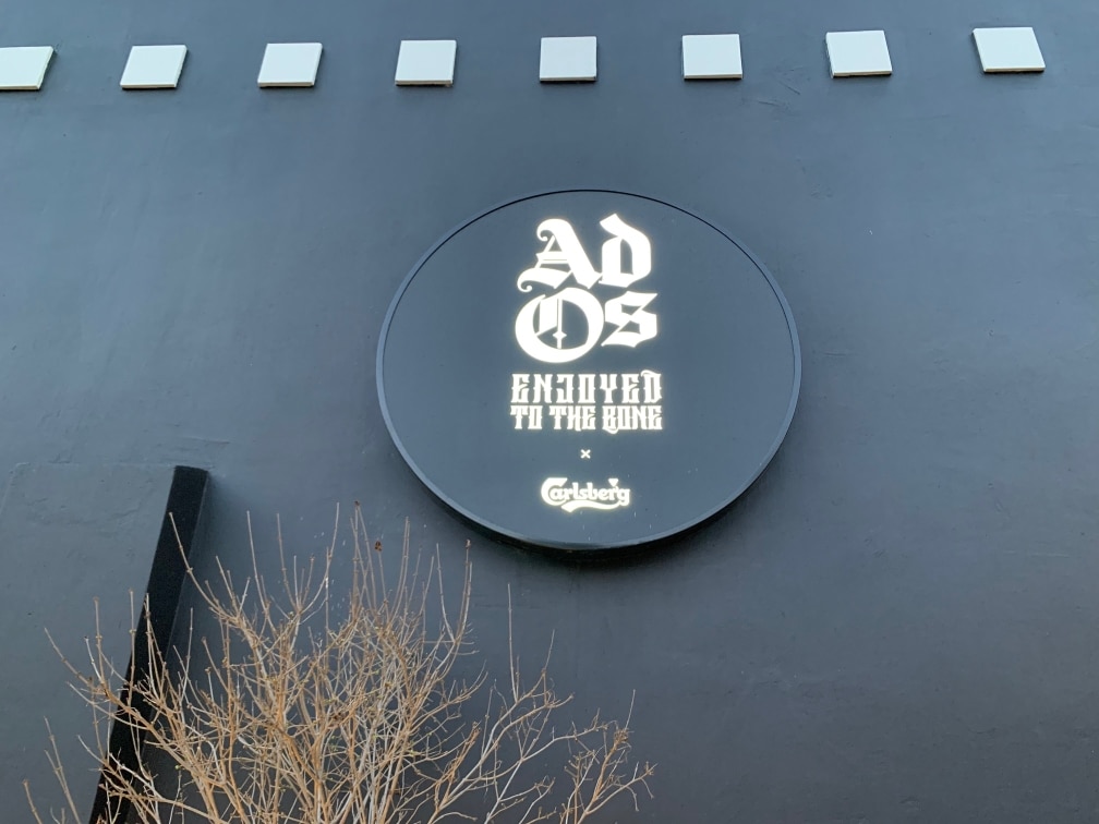 Logo lumineux Ad Os sur la façade d'un restaurant traité acoustiquement