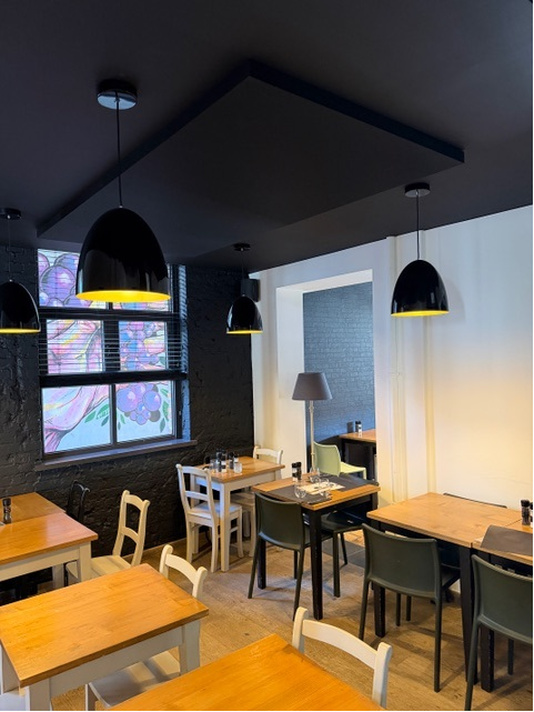 Îlot de plafond acoustique foncé avec suspensions noires dans un restaurant chaleureux