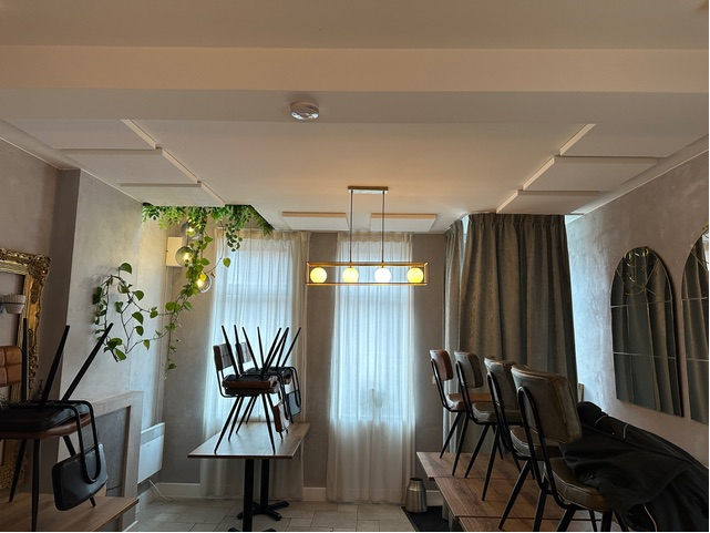 Panneaux muraux acoustiques blancs dans une salle à manger intime à l'éclairage d'ambiance