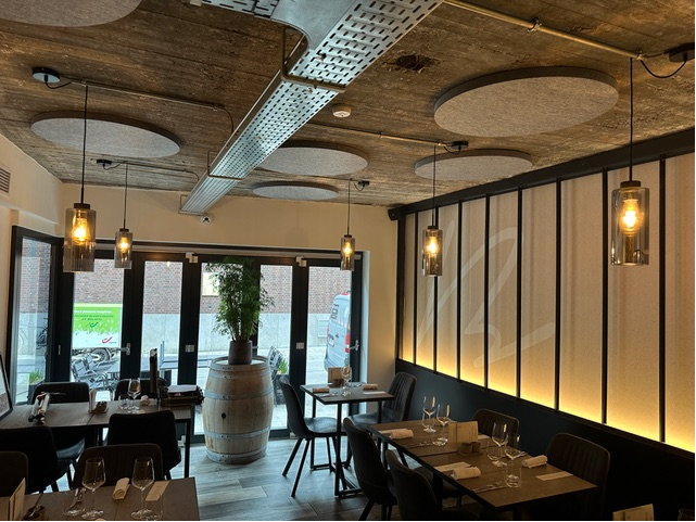 Îlots de plafond acoustiques ronds gris sous plafond béton dans un bar à vin