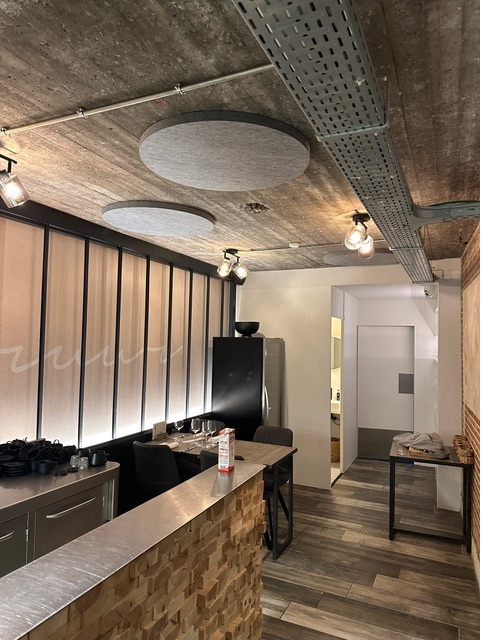 Îlots de plafond acoustiques ronds gris au-dessus du bar d'un restaurant industriel