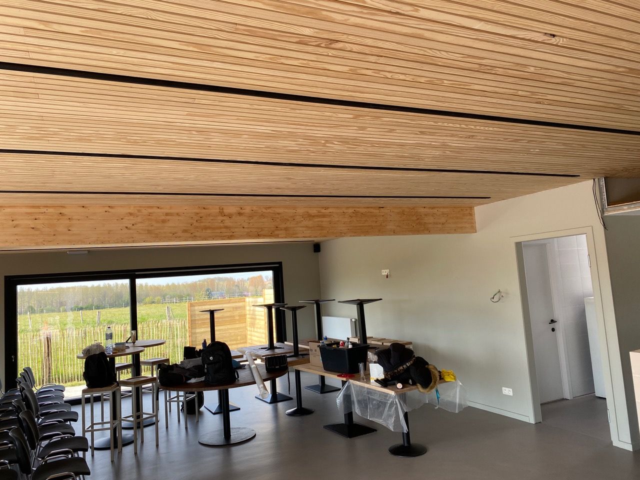 Plafond acoustique en lattes de bois dans une salle à manger avec vue jardin