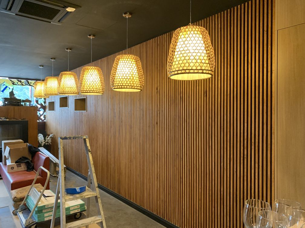 Mur acoustique en lattes de bois dans un restaurant à l'éclairage design