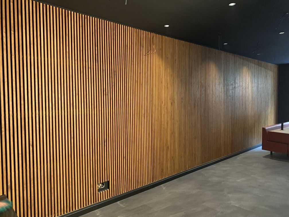 Grand mur en lattes de bois pour correction acoustique en horeca