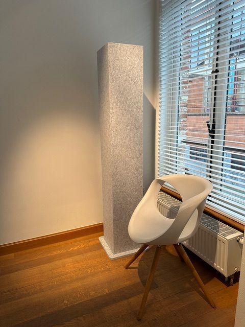 Totem acoustique gris à côté d'une chaise de bureau près de la fenêtre