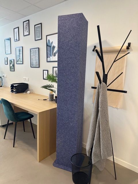 Totem acoustique bleu foncé à côté d'un poste de travail