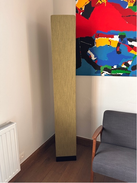 Totem acoustique jaune ocre dans un intérieur avec œuvre d'art et fauteuil
